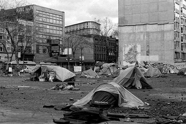A homeless tent encampment in a trash-strewn empty lot in Vancouver, Canada.