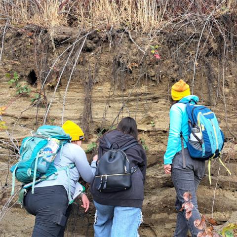 WWU geology graduate out on a field trip looking at the stratifications in the earth.