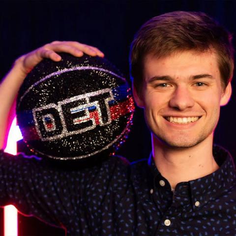 Ben Bagley holding up a bejeweled Basketball with the letters DET on it.