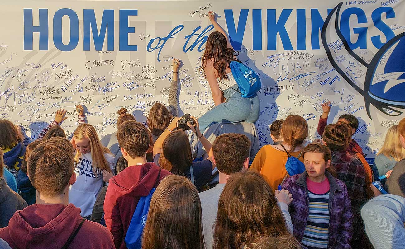 Students signing Home of the Vikings banner at the Paint B'ham Blue for WWU event