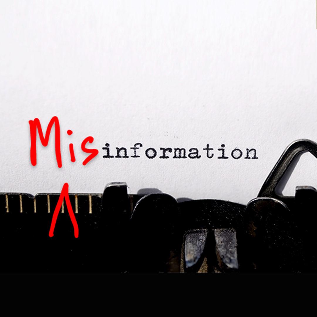 "Mis" is scrawled in bright red in front of the word "information" on a white piece of paper in an old-fashioned typewriter to make the word misinformation. 